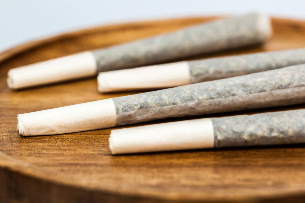 A close up of four cigarettes on a wooden tray