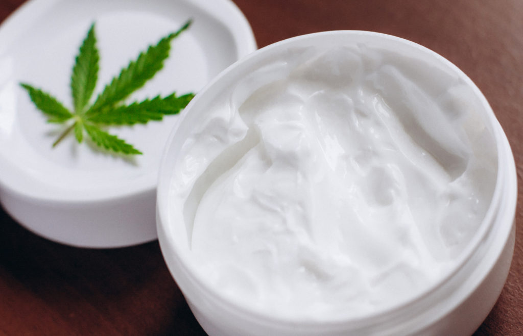 A container of cream with a marijuana leaf in it